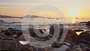 Time lapse sunset in the crystal ball on the rock at Kalim beach Phuket Thailand.