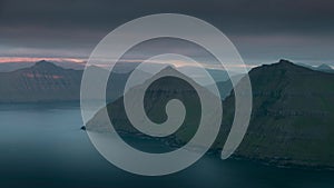 Time lapse of sunset in the fjord at viewpoint Hvithamar with moving clouds over mountains and island Kalsoy, Faroe Islands