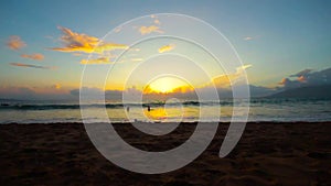 Time-lapse of a sunset over the beach with people.