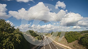 Time lapse of traffic on the highway with cars and lights moving, seen from above, with a beautiful panorama of fields and