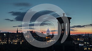 Time lapse view of Edinburgh city centre with monument and moving clouds at sunset