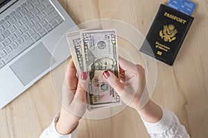 Time lapse. woman hold banknote 50 U.S. dollars in hand and count it. American passport with boarding pass and laptop on the table