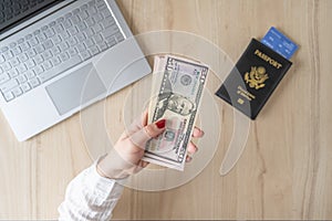 Time lapse. woman hold banknote 50 U.S. dollars in hand and count it. American passport with boarding pass and laptop on the table
