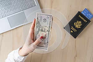 Time lapse. woman hold banknote 50 U.S. dollars in hand and count it. American passport with boarding pass and laptop on the table