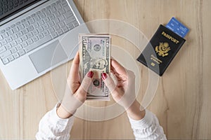 Time lapse. woman hold banknote 50 U.S. dollars in hand and count it. American passport with boarding pass and laptop on the table