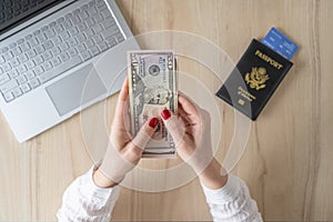 Time lapse. woman hold banknote 50 U.S. dollars in hand and count it. American passport with boarding pass and laptop on the table