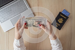 Time lapse. woman hold banknote 50 U.S. dollars in hand and count it. American passport with boarding pass and laptop on the table