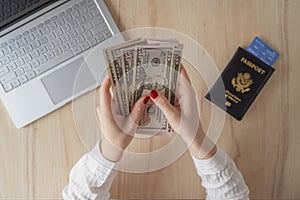 Time lapse. woman hold banknote 50 U.S. dollars in hand and count it. American passport with boarding pass and laptop on the table