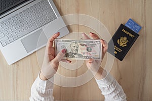 Time lapse. woman hold banknote 50 U.S. dollars in hand and count it. American passport with boarding pass and laptop on the table