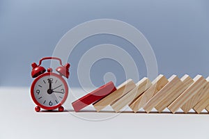 Time-limit. Lack of time and deadline. Domino effect. Red alarm clock and wooden block, copy space. Running out of time