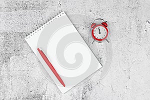 Time management concept. To-do list: red alarm clock, pencil and notebook