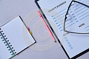 Time management deadline and schedule concept: schedule sheet, glasses and notebook on grey background