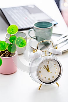 Time management and procrastination concept. Composition with alarm clock on white desk, laptop computer