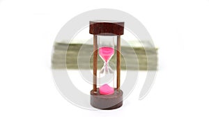 Time Is Money With Blurred Stack Of Cash Behind A Wood Sand Timer Up Front And In Focus