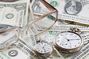 Time is money finance concept with old vintage clocks, dollar bills, spectacles