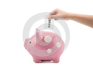 Time and money - hand putting a save into a pink piggy bank