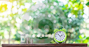 Time is Money represented by green alarm clock, a stack of dollar bills, and coins