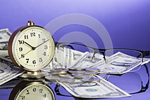 Time is money, vintage clock on cash american dollar bills, coins and glasses with nice blue background. Business Commerce concept