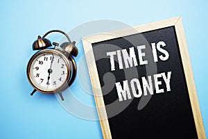 Time is Money word with alarm clock on blue background