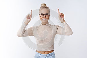 Time move forward. Portrait of attractive glamour and stylish blond woman in trendy glasses pointing up and smiling