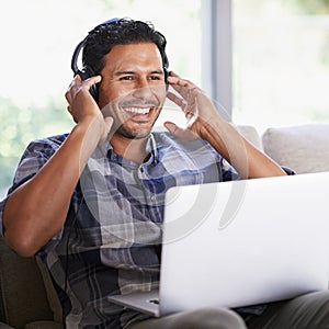 Time for a multimedia experience. A young man listening to music on his laptop at home.