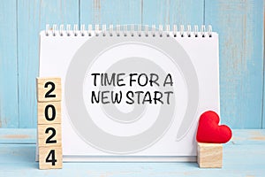 Time for A New Start words and 2024 cubes with red heart shape decoration on blue wooden table background. New Year NewYou, Goal,