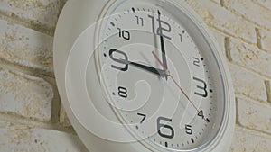 Time nine hours. Timelapse. Round white clock hanging on brick wall.