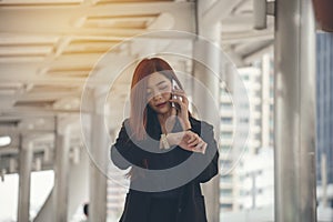 Time out concept.Urgent work,business woman seeing wrist watch and using mobile phone before meeting.Smart woman check the