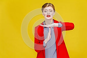 Time out! Unhappy business woman in red suit showing pause sign.