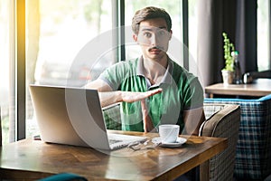 Time out! Young businessman in green t-shirt sitting and looking at camera and hope to take more time to work or want small pause