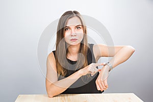 Time is over. Attractive brunette woman pointing to her hand reminding about time