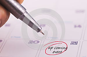 Cropped hand holding grey pen and word  UPCOMING EVENT written on calendar photo