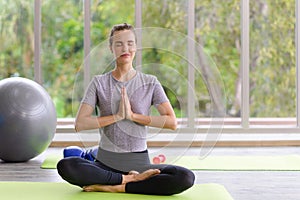 Time for practicing yoga. Young attractive woman sitting in Ardha Padmasana exercise, Lotus pose on meditation, closed eyes,