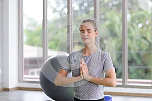 Time for practicing yoga. Young attractive woman sitting in Ardha Padmasana exercise, Lotus pose on meditation, closed eyes