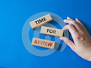 Time for Review symbol. Wooden blocks with words Time for Review. Beautiful blue background. Businessman hand. Business and Time