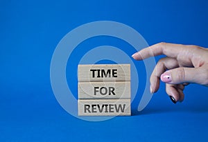 Time for Review symbol. Wooden blocks with words Time for Review. Beautiful blue background. Businessman hand. Business and Time