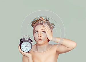 Time ruins my beauty. Anxious young woman looking up holding alarm clock. Time pressure concept