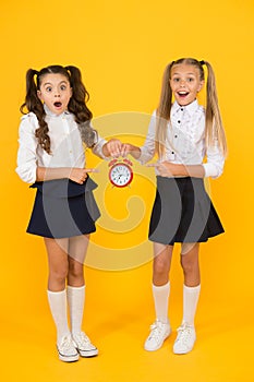 It is time. School schedule. Schoolgirls and alarm clock. Children school pupils. Knowledge day. School time. Surprised