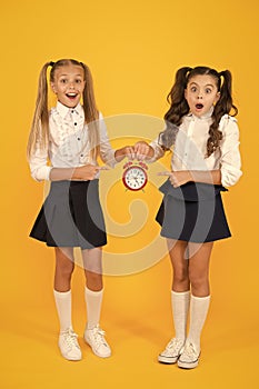 It is time. School schedule. Schoolgirls and alarm clock. Children school pupils. Knowledge day. School time. Surprised