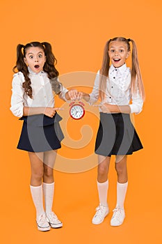 It is time. School schedule. Schoolgirls and alarm clock. Children school pupils. Knowledge day. School time. Surprised