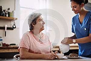 Time for some afternoon tea. an attractive young female caregiver pouring a cup of tea for a senior patient in a nursing