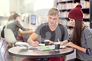 Time for some revision. two college students studying together at the library.
