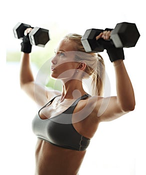 Time for something a bit heavier. a beautiful young woman in workout gear lifting dumbbells.