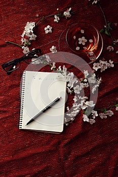Time for tea, empty notebook, pen and cherry flowers on table