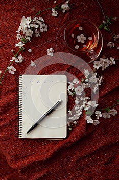 Time for tea, empty notebook, pen and cherry flowers on table