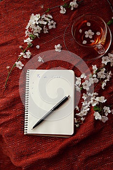Time for tea, empty notebook, pen and cherry flowers on table