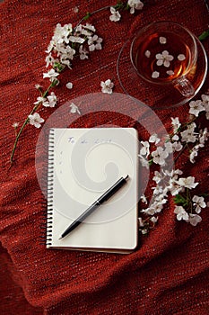 Time for tea, empty notebook, pen and cherry flowers on table