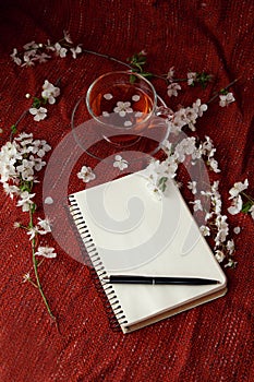 Time for tea, empty notebook, pen and cherry flowers on table