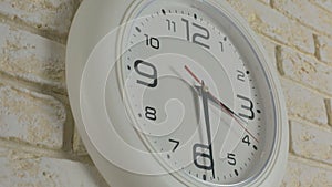 Time three hours thirty minutes. Timelapse. Round white clock hanging on brick wall.