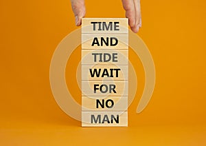 Time to action symbol. Wooden blocks with words time and tide wait for no man. Beautiful orange background. Businessman hand.
